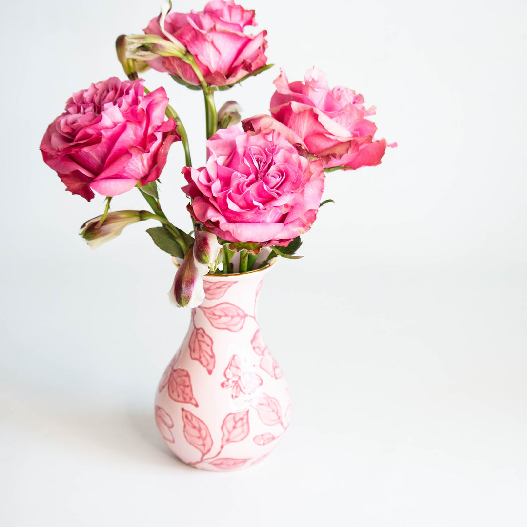 Pink blossom chinoiserie vase holding a bouquet of magenta garden roses against a white backdrop