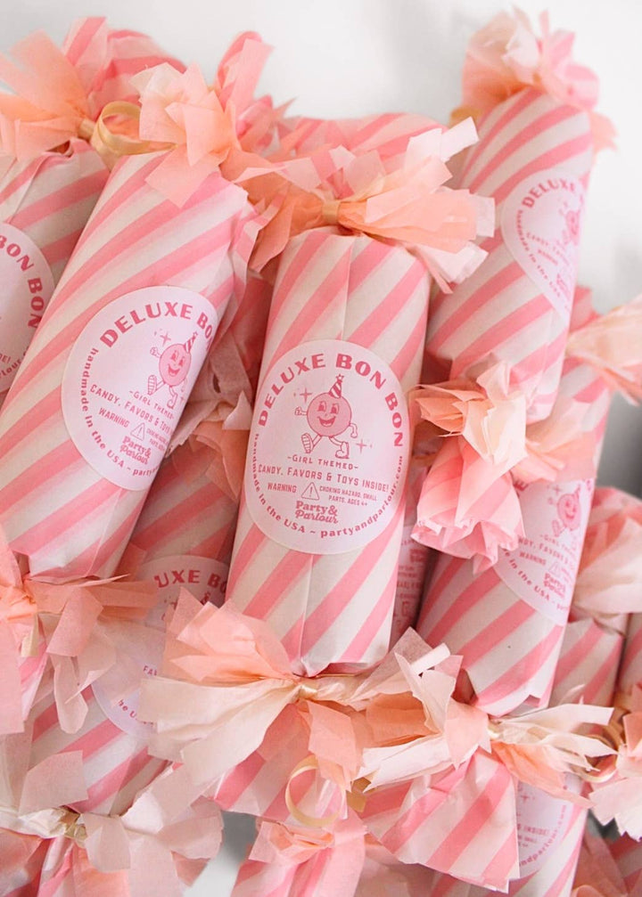 Rows of pink striped surprise bon bons with peach pom poms, ready as tea party favors