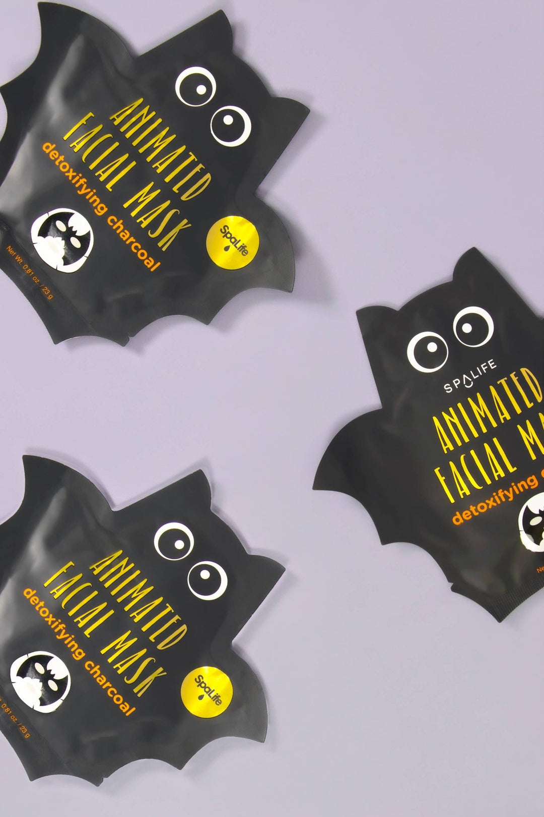 Three bat shaped charcoal mask pouches scattered on a lavender backdrop, cute boo basket stuffers