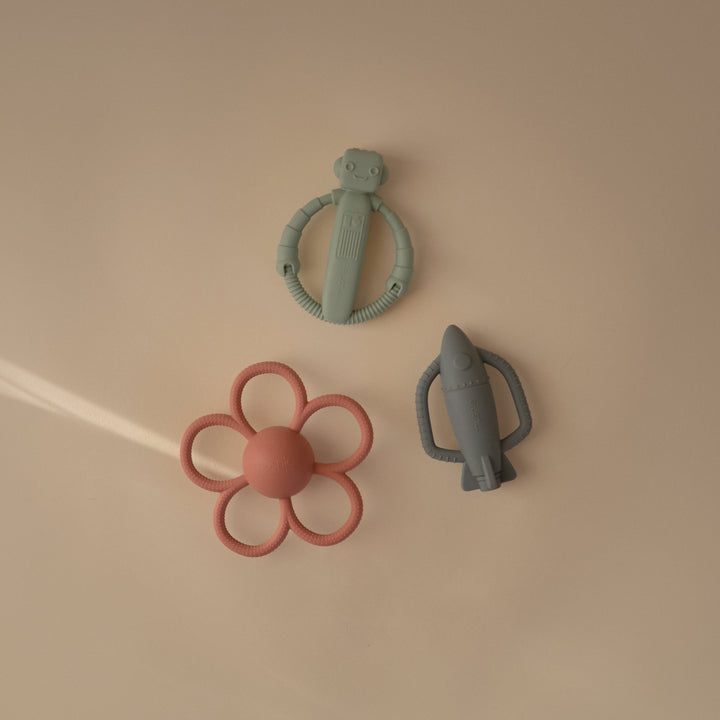 Flat lay of the Mushie rocket and robot silicone rattle teethers