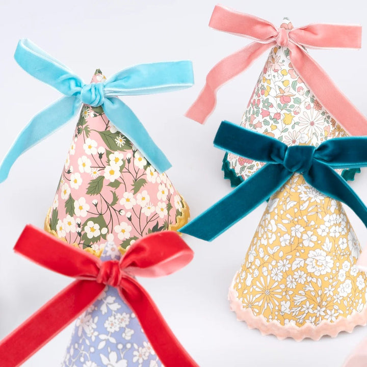 Decorative paper hats with floral patterns and colorful ribbons on a white background