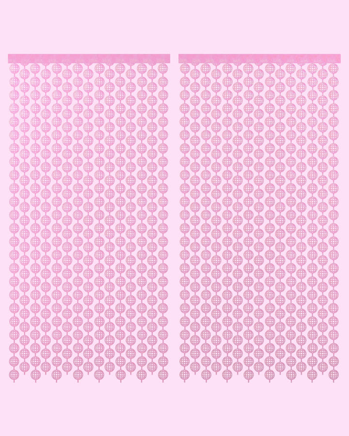 Two pink disco ball foil curtain panels hung side by side on a pale pink wall