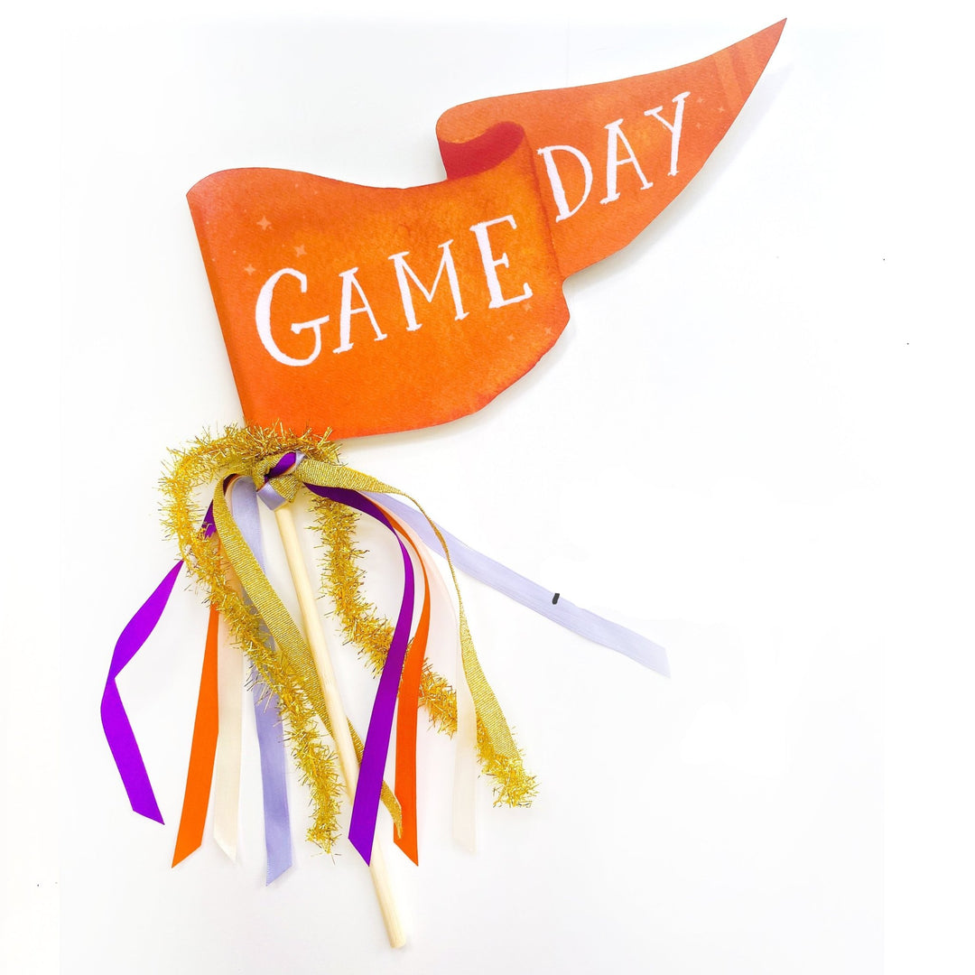 Orange Game Day pennant flag with purple, orange, and cream ribbons and gold tinsel on a wood dowel