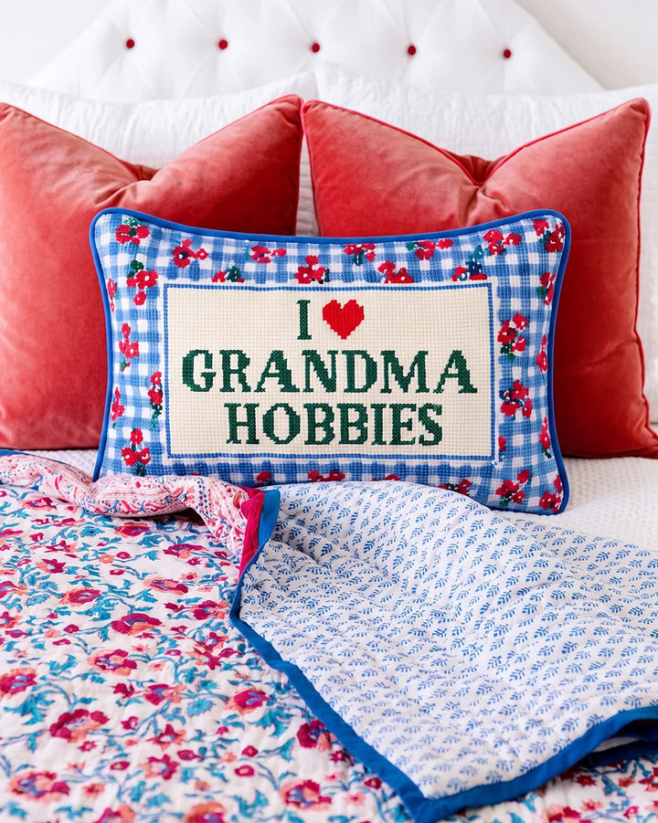 Grandma Hobbies pillow on a bed in front of coral velvet pillows and a pink floral quilt