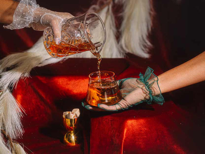 Hand holding a holiday bourbon old fashioned in a glass mug