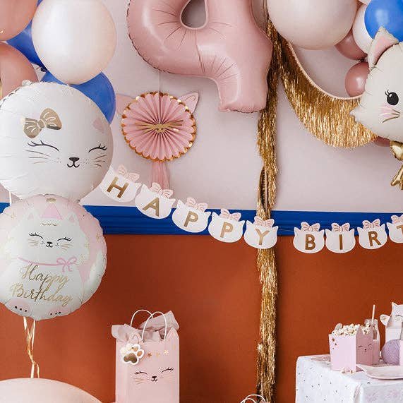 Cat birthday balloons with a Happy Birthday kitty banner and pink fan decoration on an orange wall