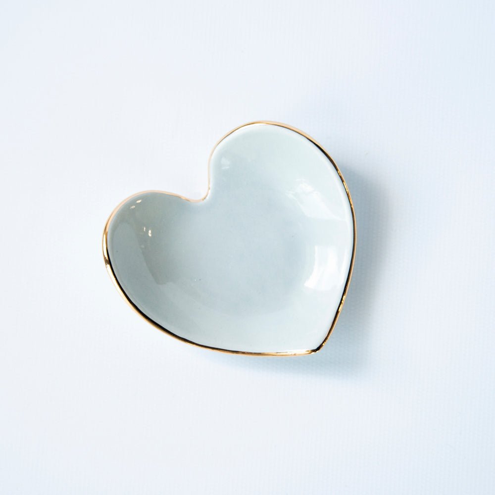 Pale aqua heart ring dish with a gold edge, angled view