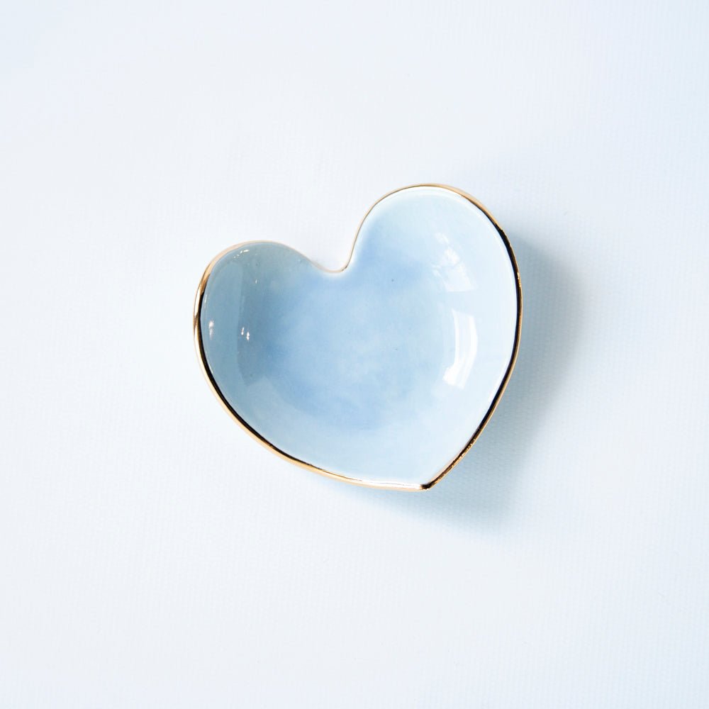 Light blue heart ring dish with a thin gold rim on a white background