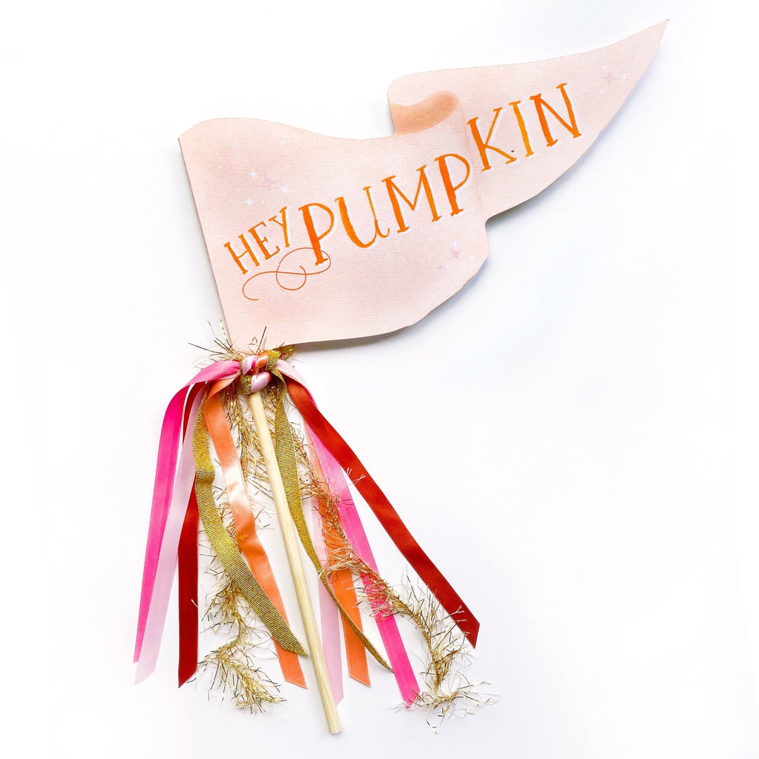 Cream Hey Pumpkin pennant flag with orange lettering and pink, orange, and red ribbons with gold tinsel on a wood dowel