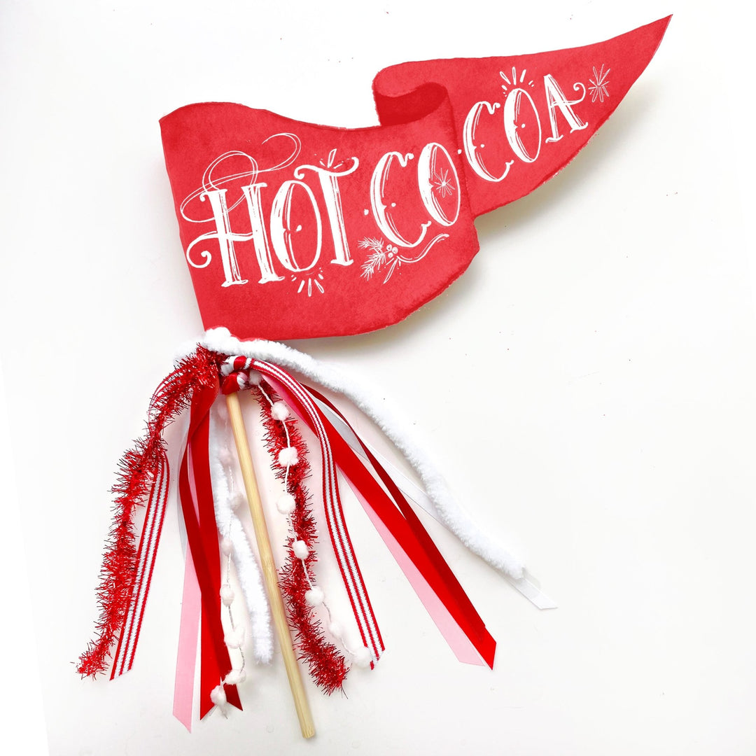 Red Hot Cocoa pennant flag with red-striped ribbons, white marshmallow pom poms, and red tinsel on a wood dowel