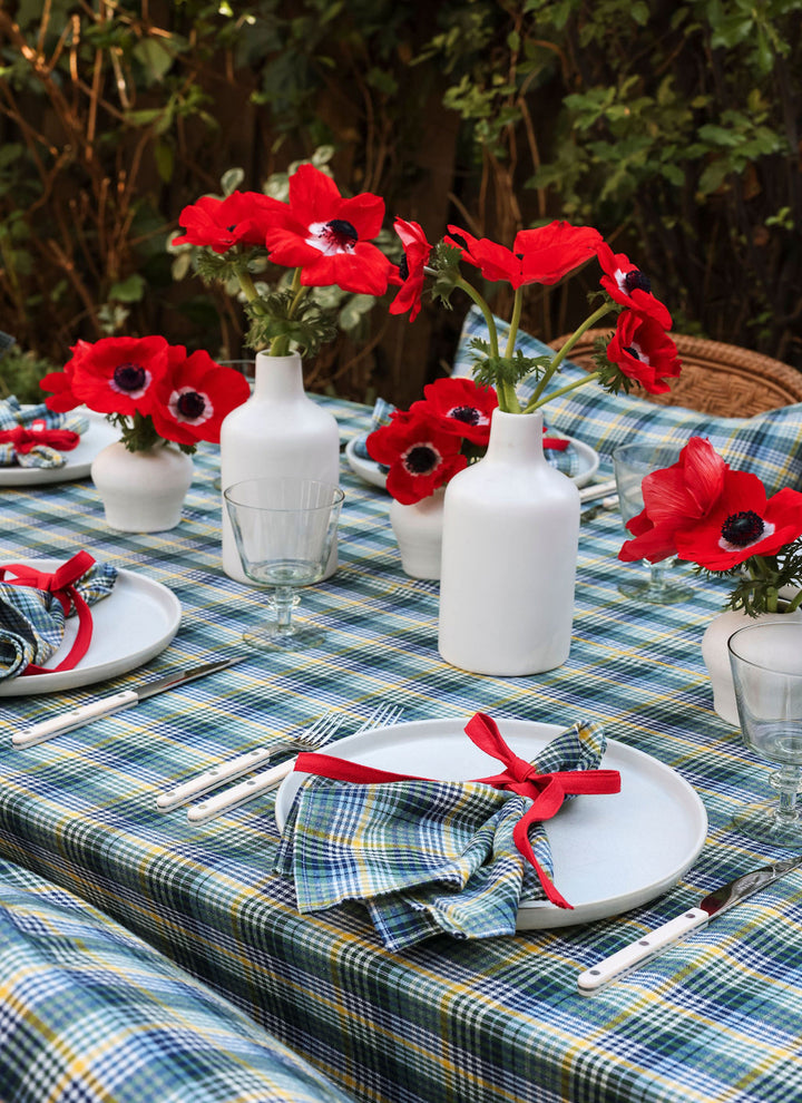 Maine plaid tablecloth in navy, yellow, and green set outdoors with red anemones and candles