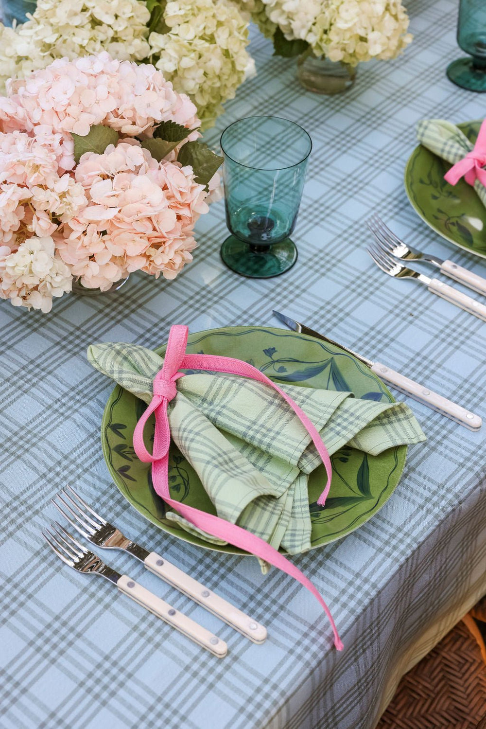 Sprout green napkins on a spring table with hydrangea, green glassware, and blue gingham