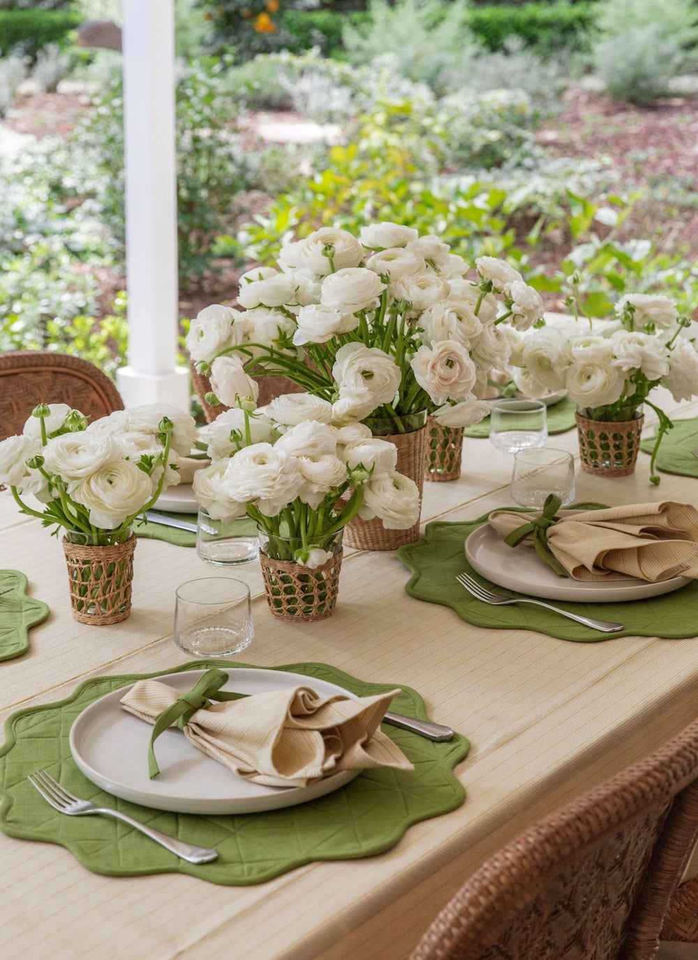 Porch table dressed in a butter striped tablecloth with green scalloped placemats and ranunculus