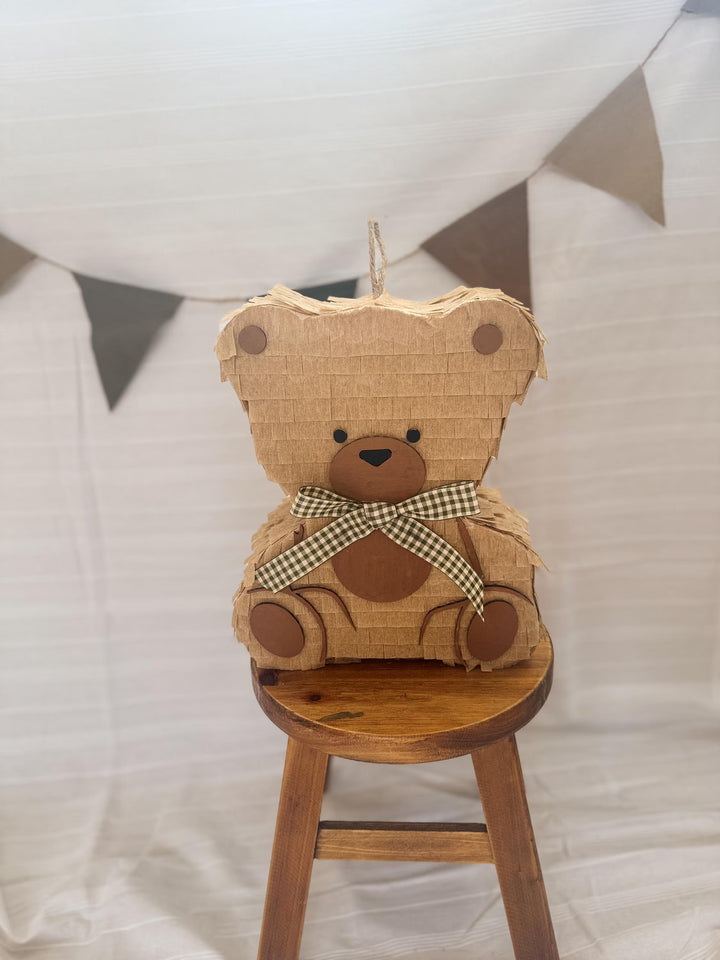 Teddy bear pinata decoration on a wooden stool with a white background