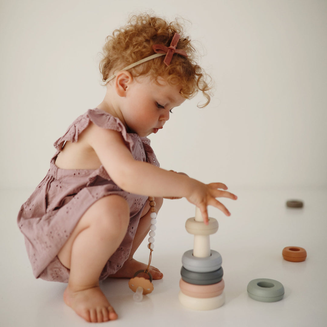 Baby playing with toys from the Mushie everyday play gift set