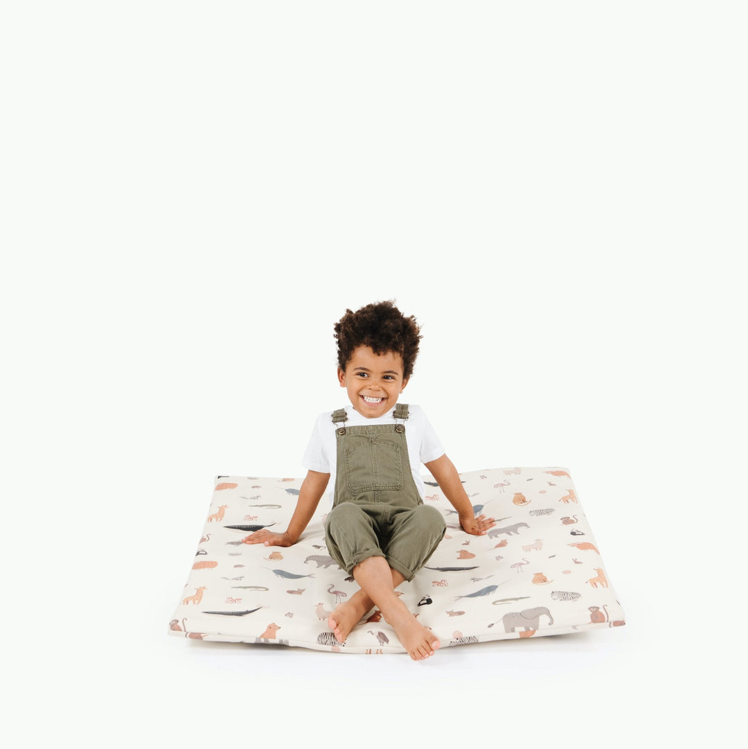 Boy sitting on the square Menagerie animal print padded play mat