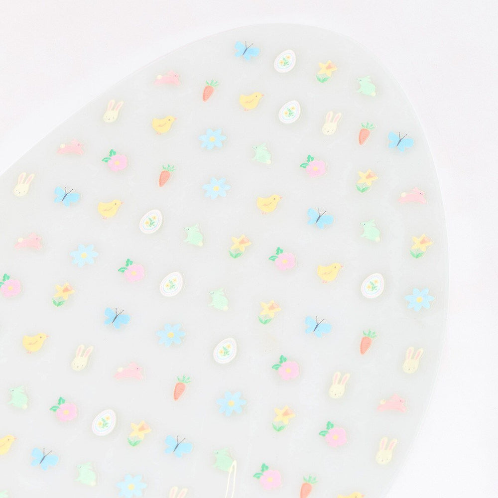 Close-up of pastel Easter nail stickers with tiny bunnies, chicks, butterflies, carrots and flowers.