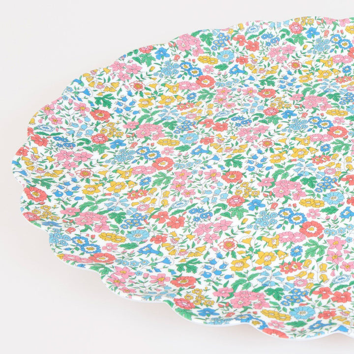 Angled close-up of the scalloped rim and colorful Liberty floral print on an oval melamine serving platter.