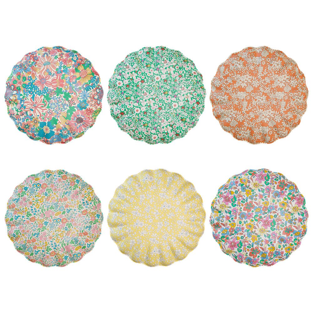 Six scalloped reusable melamine plates in assorted Liberty floral prints, arranged in two rows against white.
