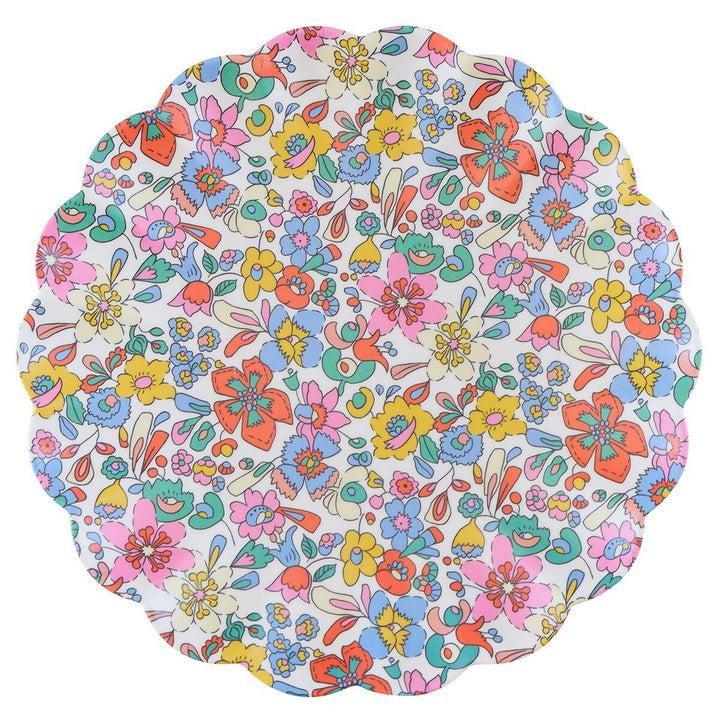 Scalloped reusable melamine plate with stylized pink, orange, blue and yellow Liberty flowers on white.