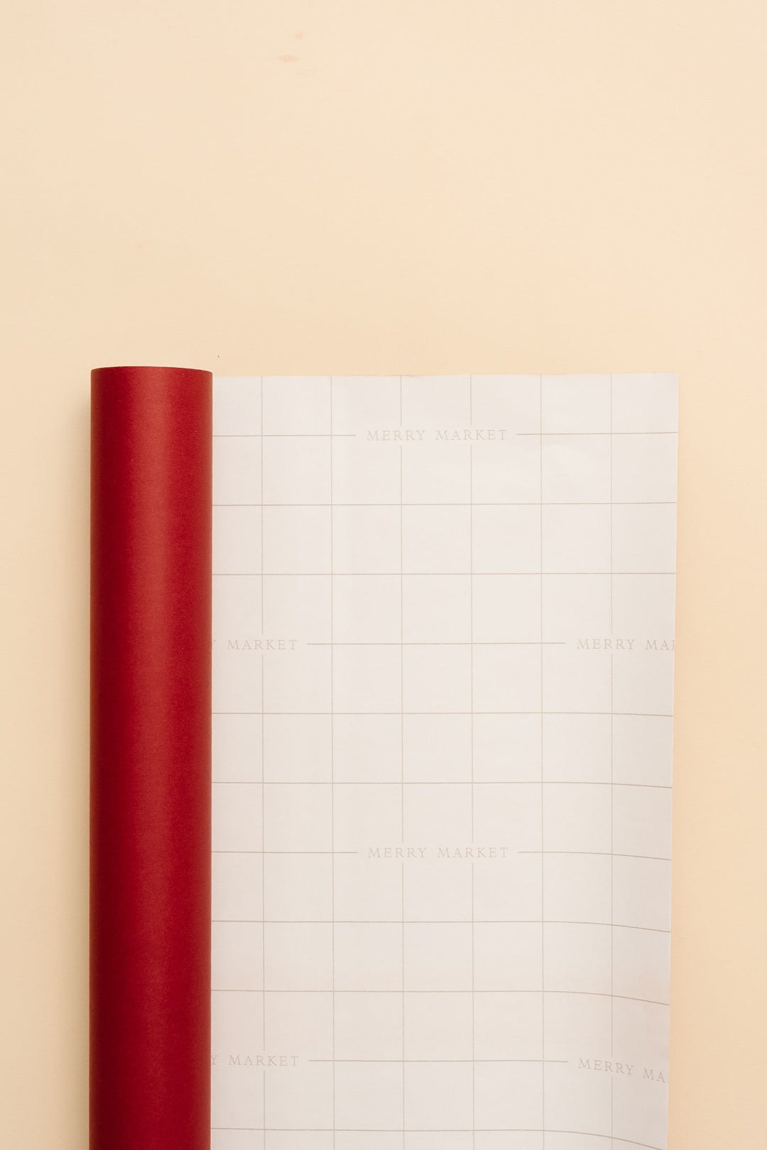 Solid red paper roll beside an unrolled sheet showing grid lines on the back for cutting
