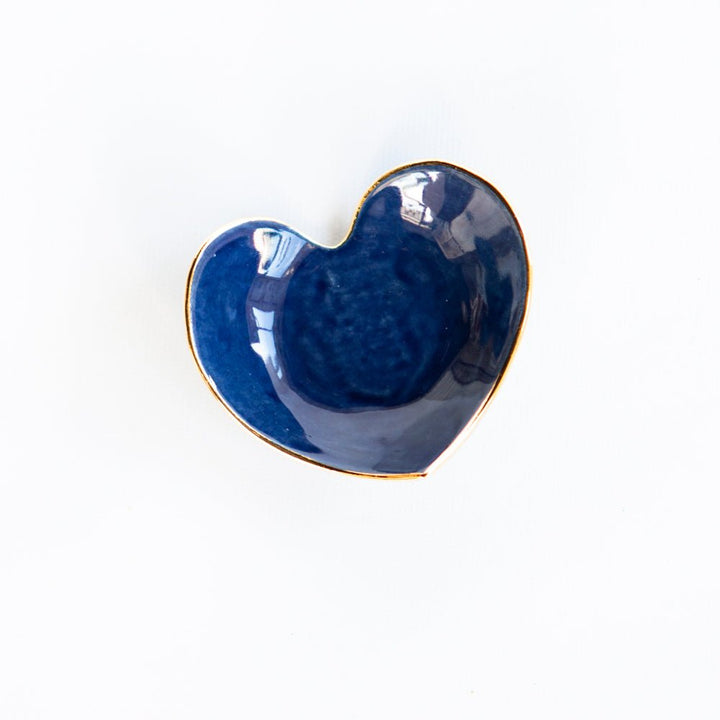 Deep navy blue heart ring dish with a glossy glaze and gold rim