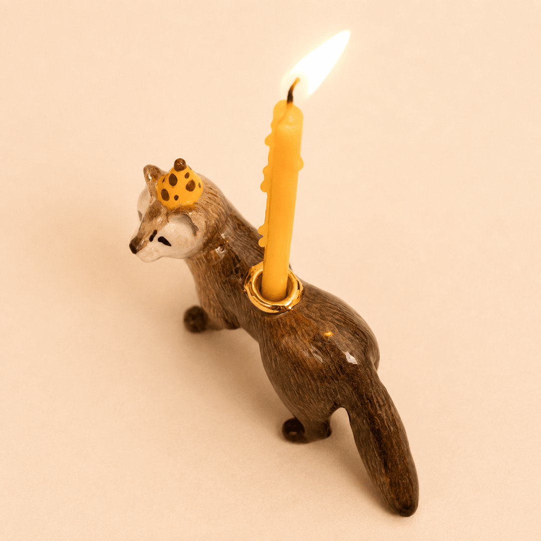 Three-quarter view of the mink cake topper with a candle burning in its gold holder