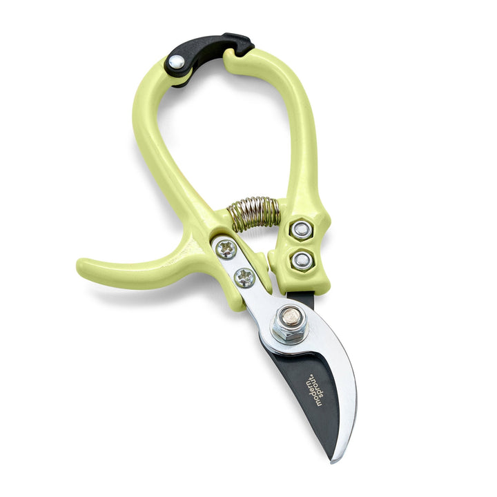 Chartreuse bypass pruners with closed curved blades and a coil spring on white
