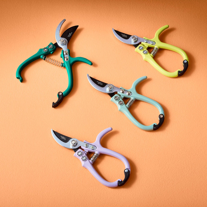 Ocean, chartreuse, sage, and lavender bypass pruners arranged on an orange backdrop