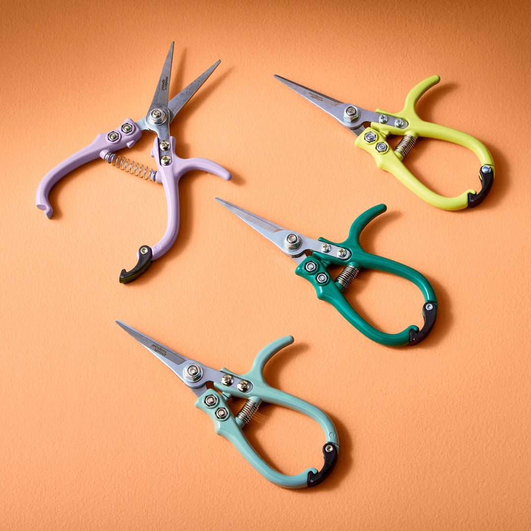 Lavender, chartreuse, ocean, and sage needle-nose garden shears on an orange backdrop
