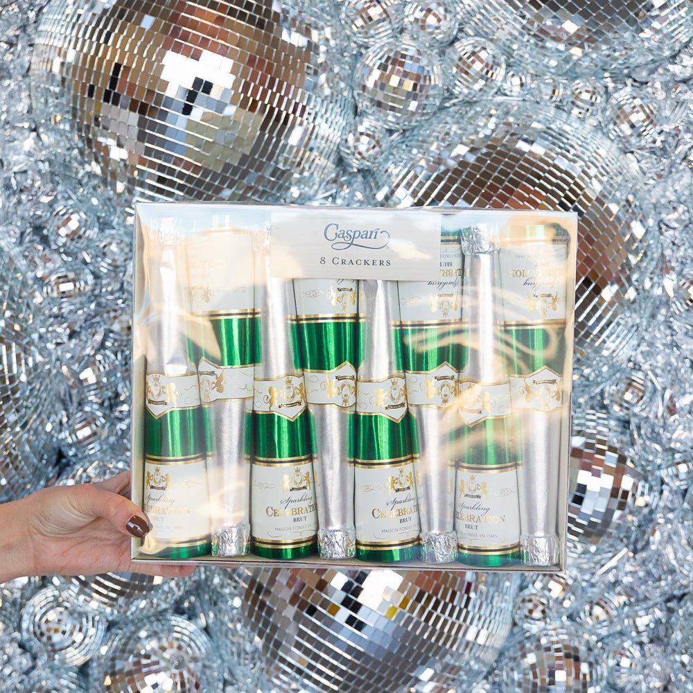 Champagne bottle celebration crackers held against a silver disco ball backdrop for a New Year's Eve party