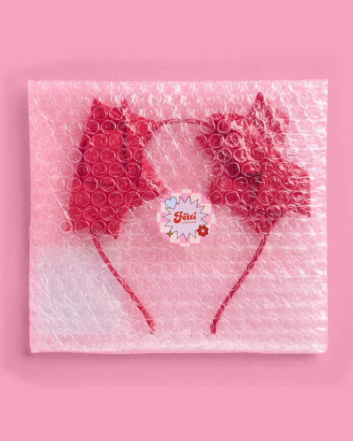 Red bow Christmas headband in clear protective packaging with a round brand sticker