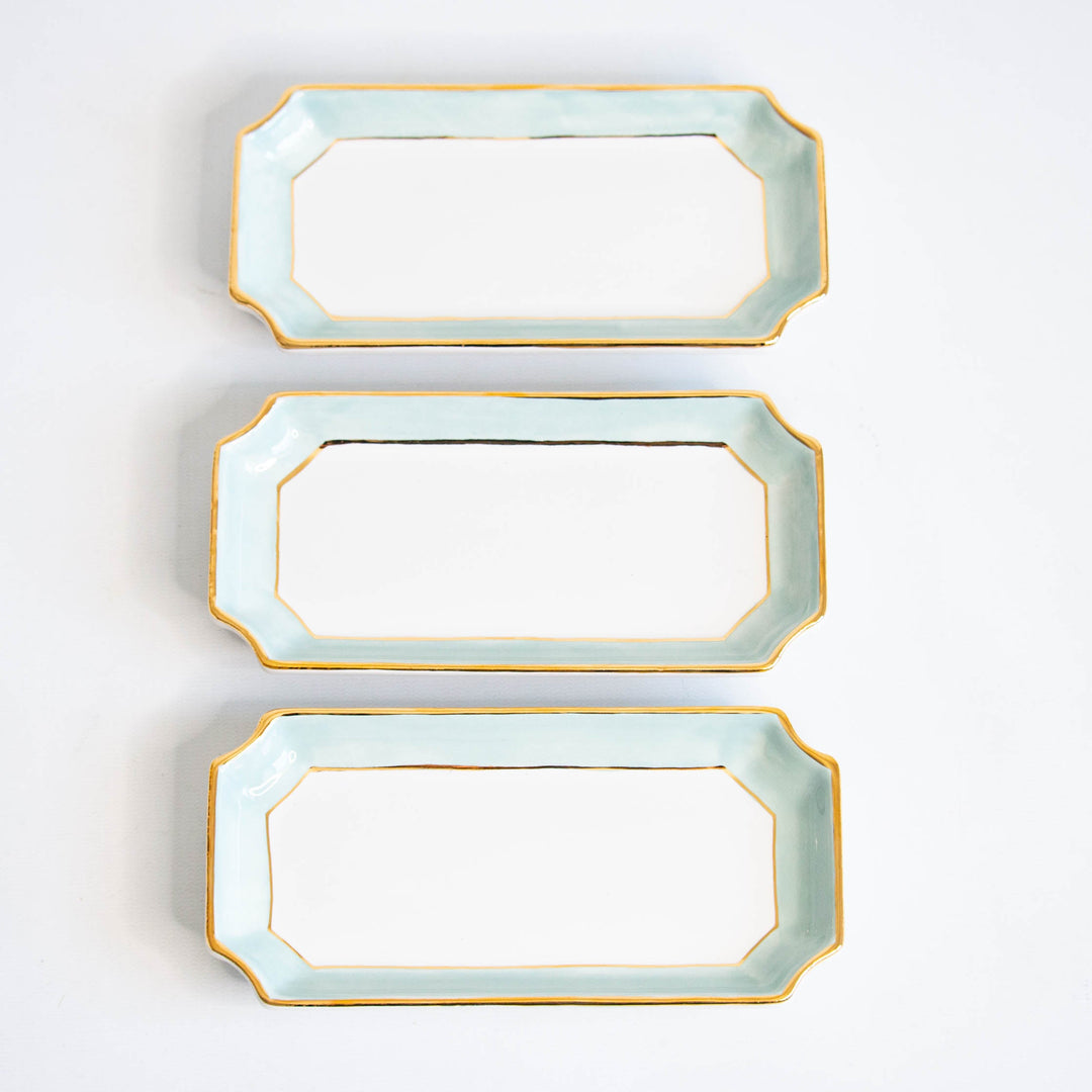 Three aquamarine petite valet trays stacked with gold rims on white, a matching set for a shower
