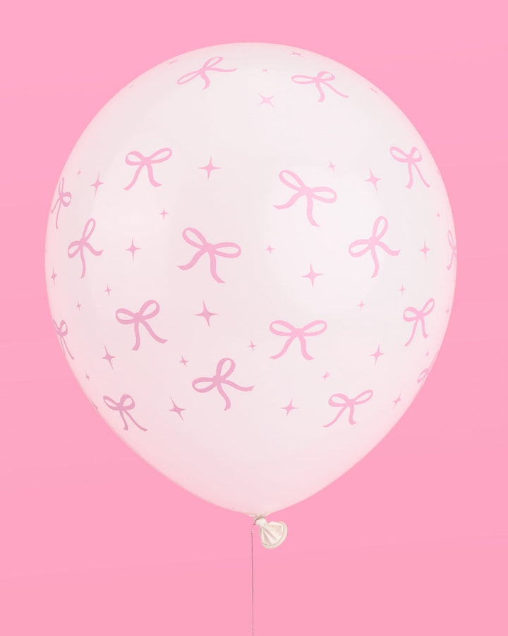 Bunch of pink bow latex balloons against a pink backdrop