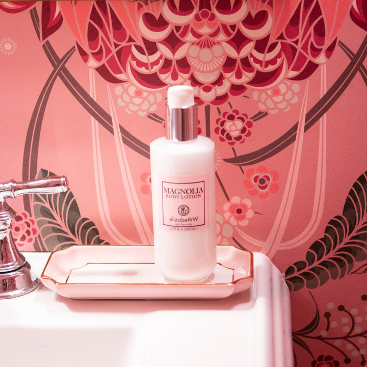 Pink petite valet tray on a vanity holding a lotion bottle against pink floral wallpaper, a spa day gift