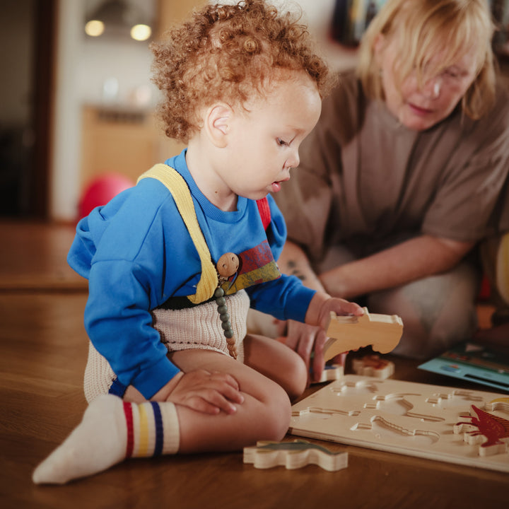 Child playing with a Mushie wooden puzzle