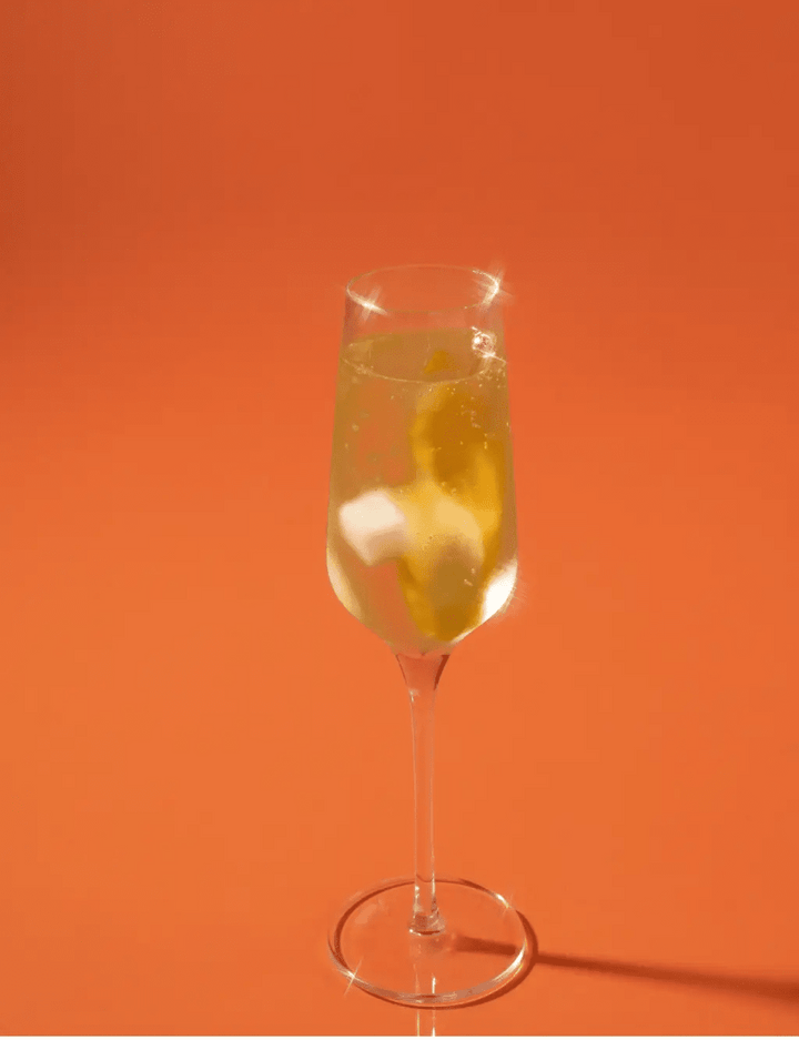 Champagne flute of mimosa made with citrus mixer cubes, styled on a brunch table with flowers