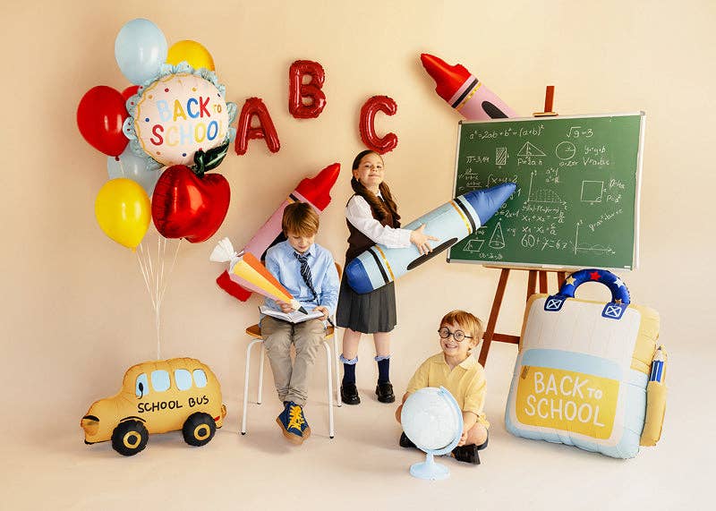 Back to School foil balloon styled in a classroom party scene with crayon, apple, and letter balloons