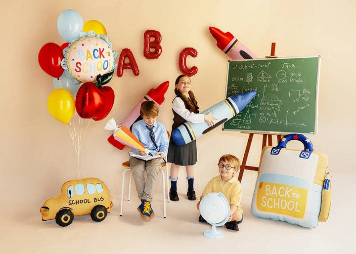 Back to School foil balloon styled in a classroom party scene with crayon, apple, and letter balloons
