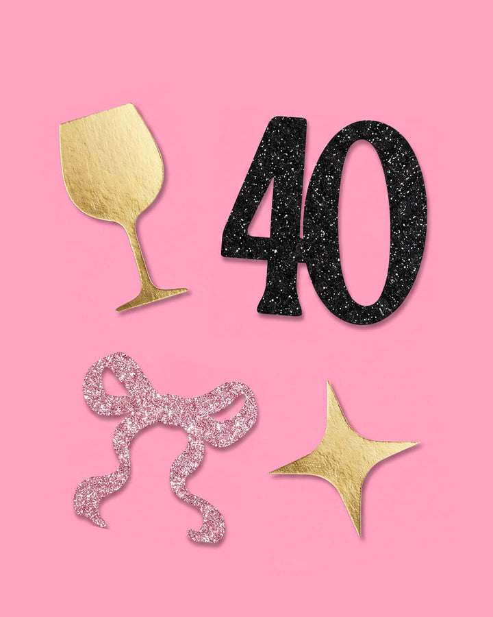 Close view of a black glitter 40, gold wine glass, pink glitter bow, and gold star