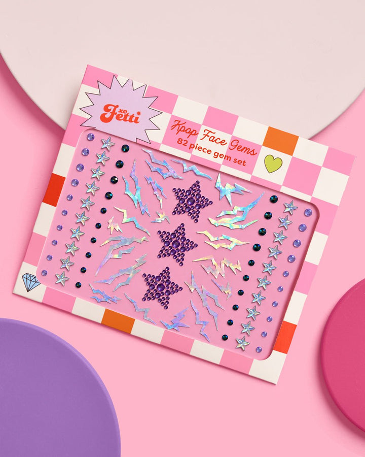 Kpop 82-piece face gem set in pink checkerboard packaging on a pink and purple background.