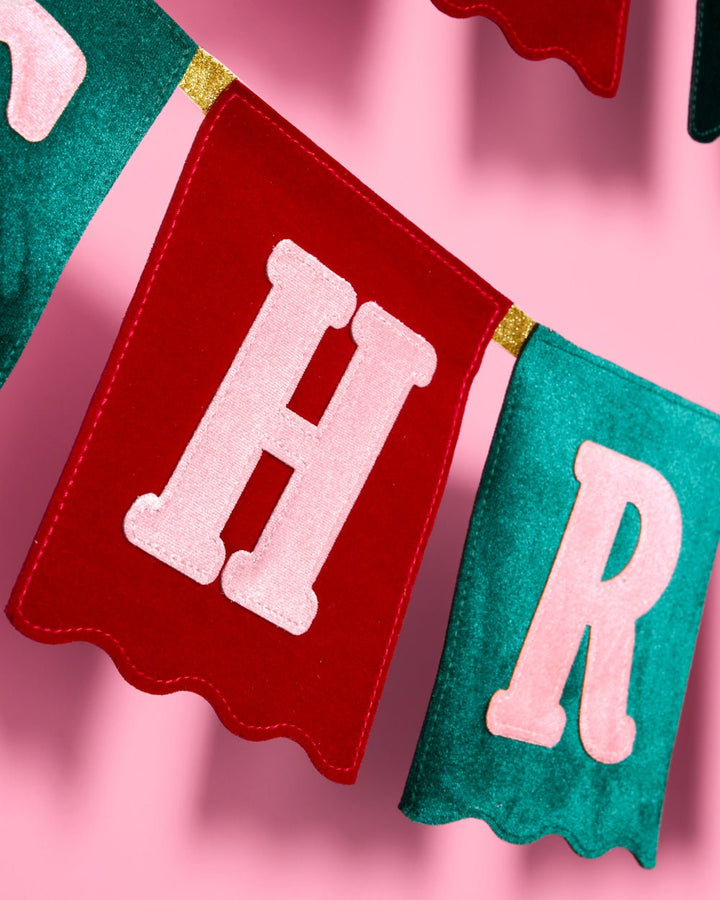 Close view of a single red velvet flag with a scalloped edge and pink letter