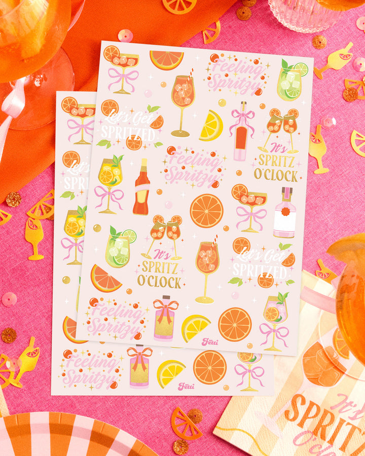 Two sheets of spritz temporary tattoos on a styled cocktail table with oranges and confetti