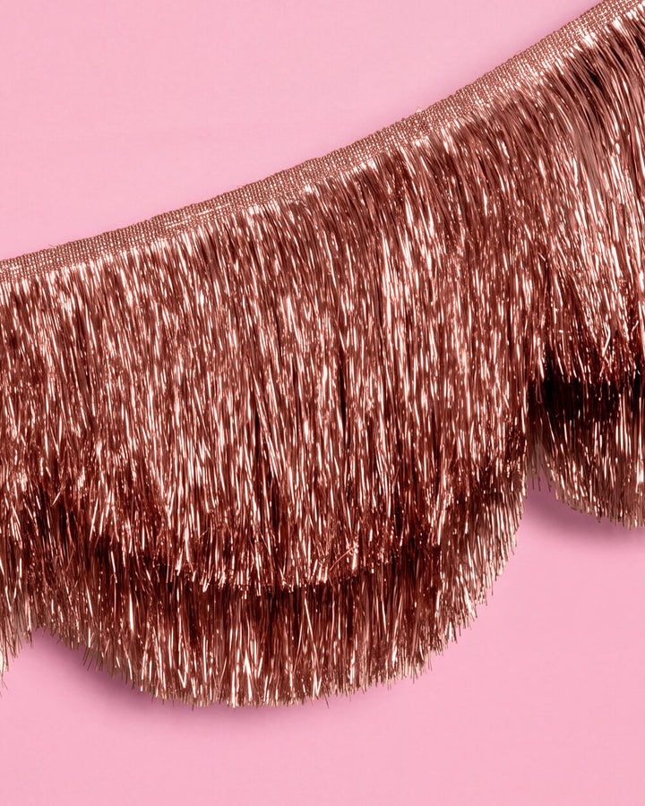 Close-up of two layers of rose gold metallic tinsel fringe in a scalloped edge