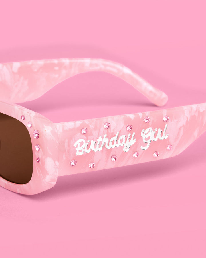 Close-up of the silver Birthday Girl script and rhinestones on the pink marble sunglasses arm