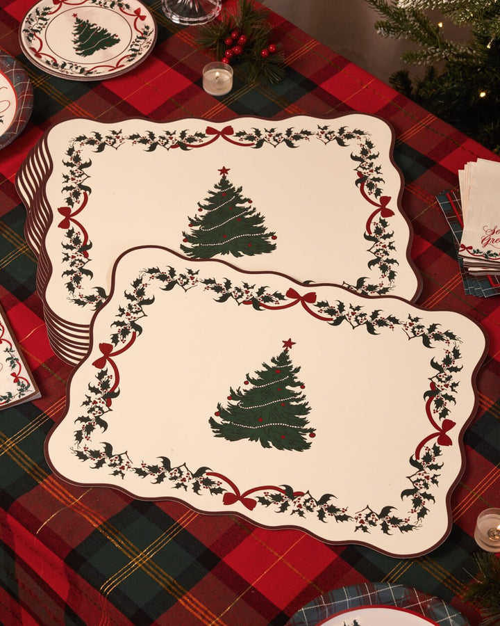 Two Christmas tree paper placemats laid over a red tartan tablecloth