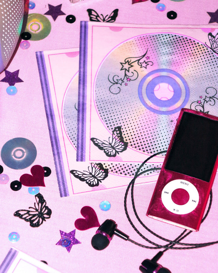 Y2K iridescent CD napkin beside a red MP3 player and scattered butterfly confetti
