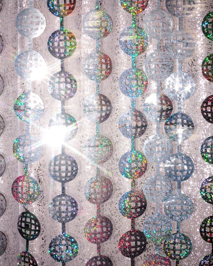 Mirrored disco ball cutouts flaring in the light on a silver foil curtain strand