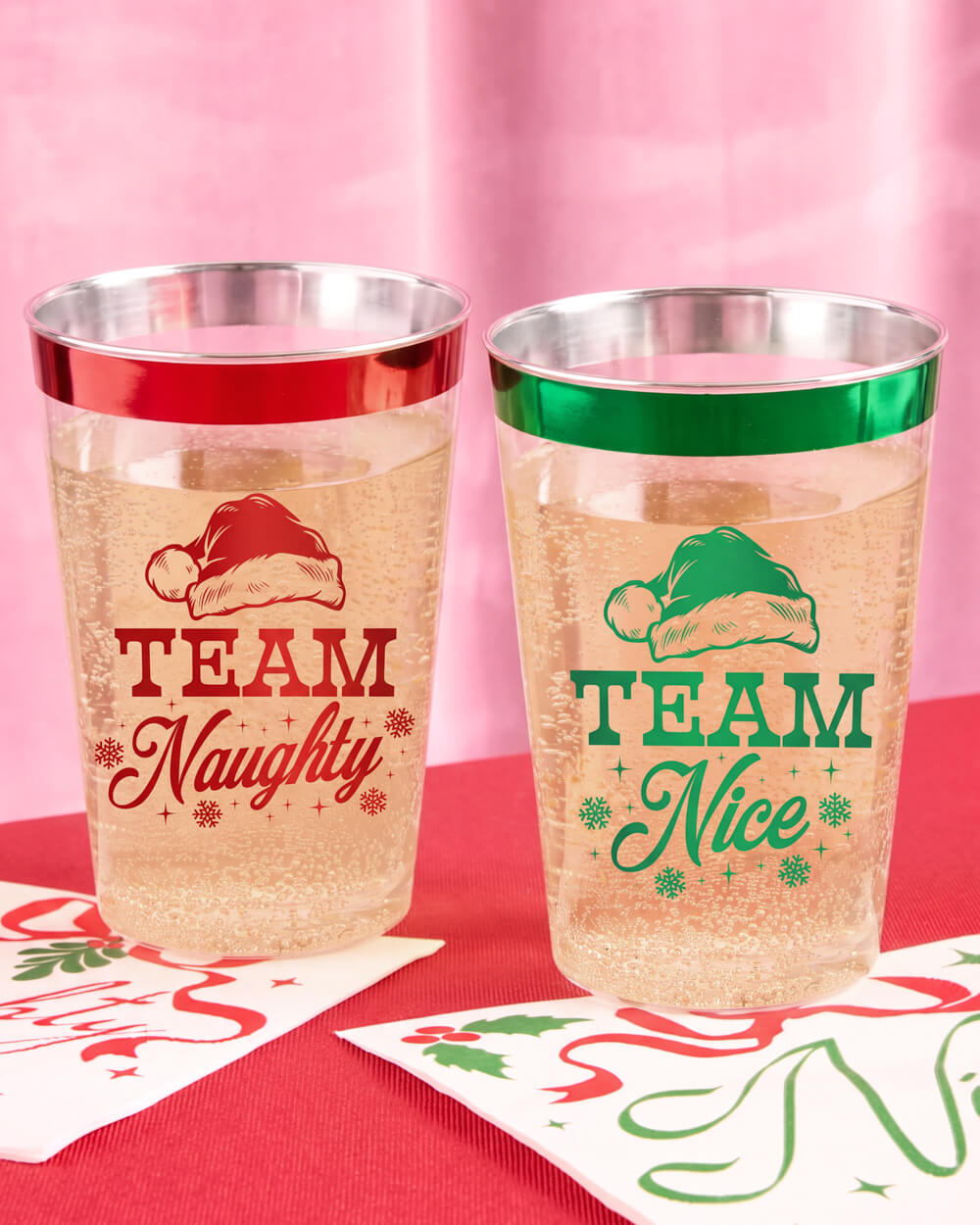 Team Naughty and Team Nice Christmas cups filled with sparkling drinks beside holiday napkins