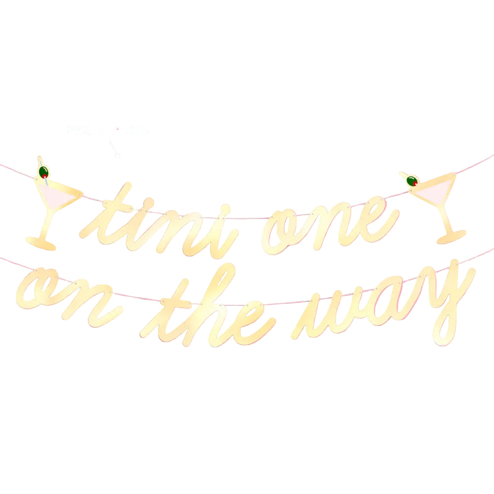 Pre-strung gold foil tini one on the way banner with a martini glass icon at each end on a pink wall